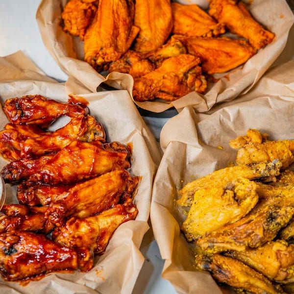 Assortment of plain, BBQ, and seasoned chicken wings in baskets with ranch dipping sauces.